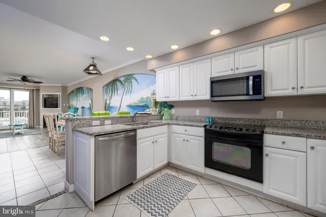 a kitchen with stainless steel appliances granite countertop a sink a stove a refrigerator cabinets and a dining table