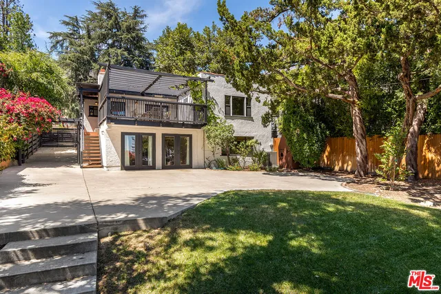 a backyard of a house with table and chairs and potted plants