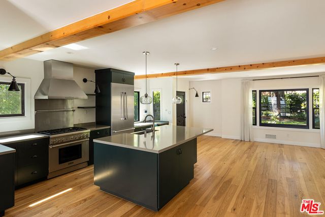 a large kitchen with stainless steel appliances wooden floor and a window