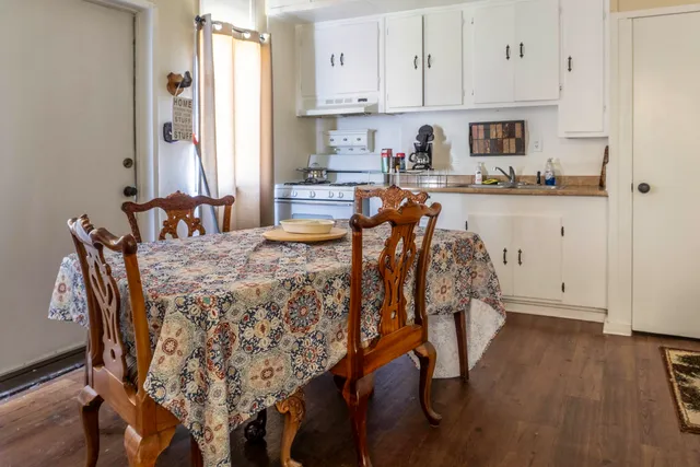 a kitchen with stainless steel appliances granite countertop a stove a sink and white cabinets with wooden floor