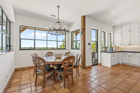 a kitchen with stainless steel appliances granite countertop a sink a stove a dining table and chairs