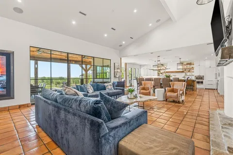 a dining hall with stainless steel appliances a dining table and chairs with the view of kitchen