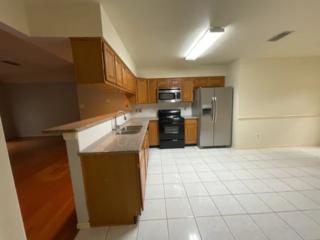 a kitchen with stainless steel appliances kitchen island granite countertop a refrigerator and a stove