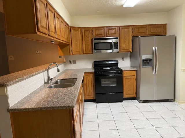 a kitchen with granite countertop a refrigerator a stove and a sink