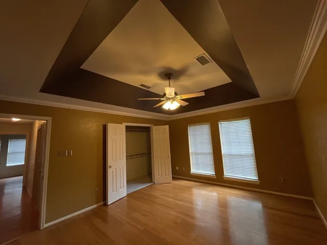 a view of an empty room with a window and chandelier fan