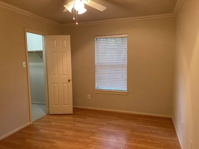 an empty room with chandelier fan and windows