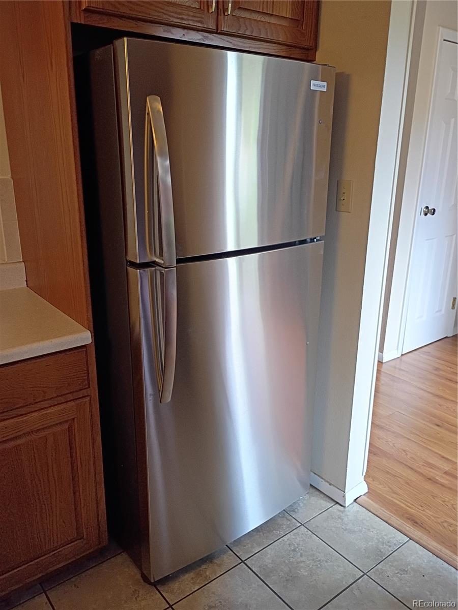 1625 West Elizabeth Street, Unit A1 Fort Collins, CO 80521 - Photo 10 of 27 a view of a refrigerator in kitchen and an empty room with wooden floor