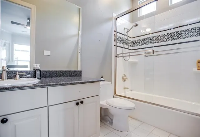 a bathroom with a granite countertop sink mirror vanity and toilet