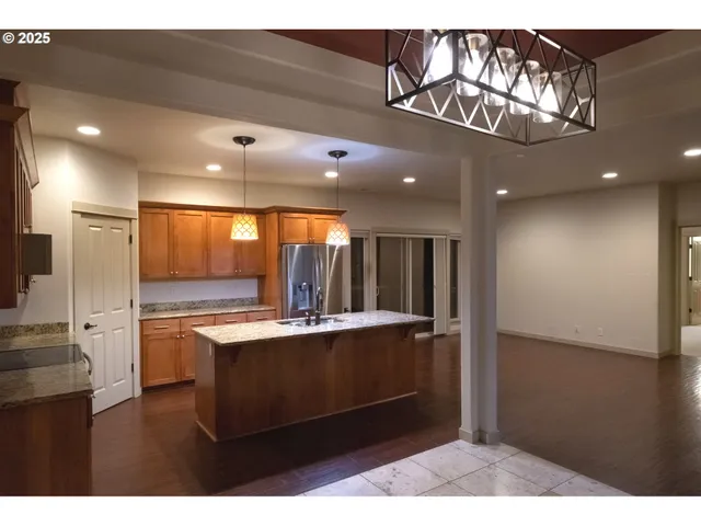a kitchen with kitchen island granite countertop wooden floors and view living room