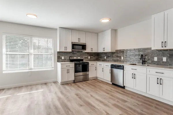 a kitchen with granite countertop white cabinets a sink a window and stainless steel appliances