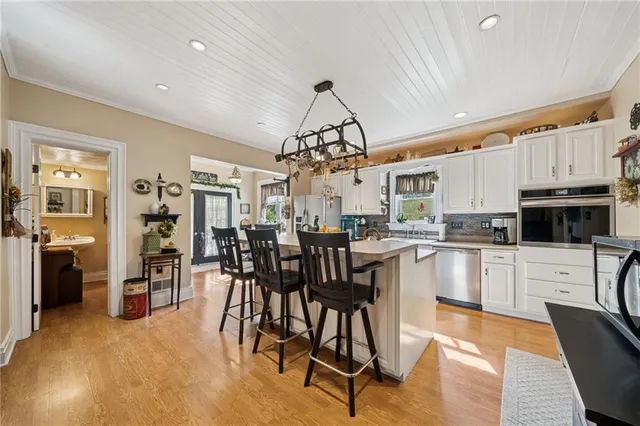 a kitchen with stainless steel appliances granite countertop a refrigerator a sink dishwasher a dining table and chairs with wooden floor