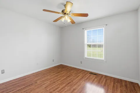 an empty room with a window and wooden floor
