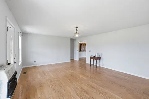 a view of an empty room with a window and wooden floor
