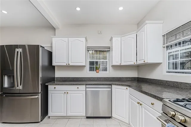 a kitchen with granite countertop white cabinets and stainless steel appliances