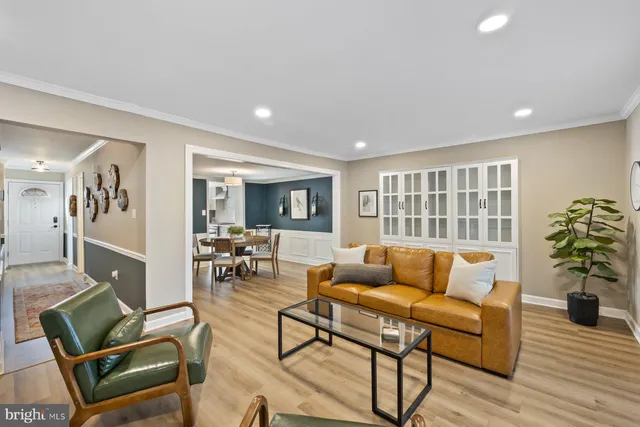 a living room with furniture and potted plants with wooden floor