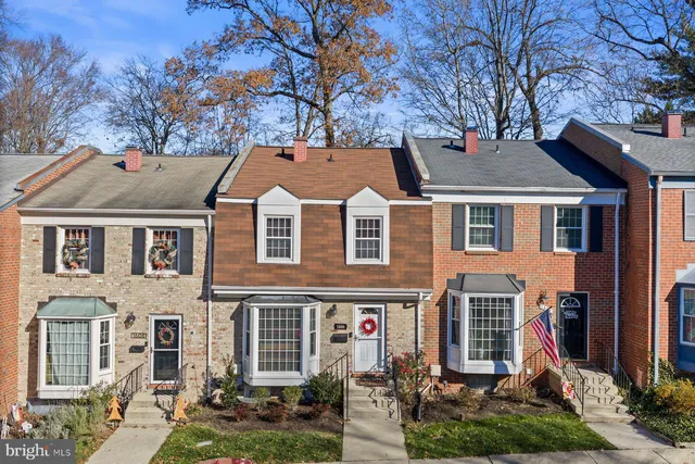 a view of a big yard in front of a brick house with large windows