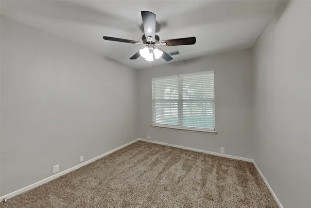 an empty room with a window and a fan
