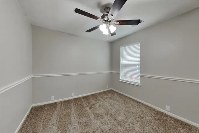 an empty room with a chandelier fan and windows