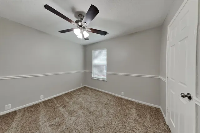 an empty room with a window and a fan