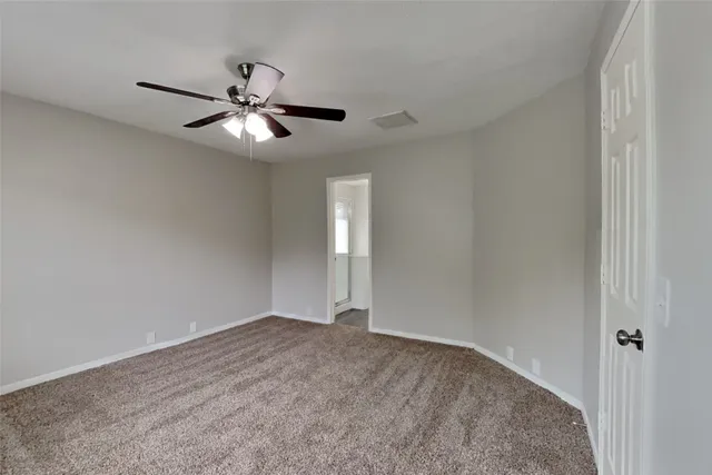 a view of an empty room and chandelier fan