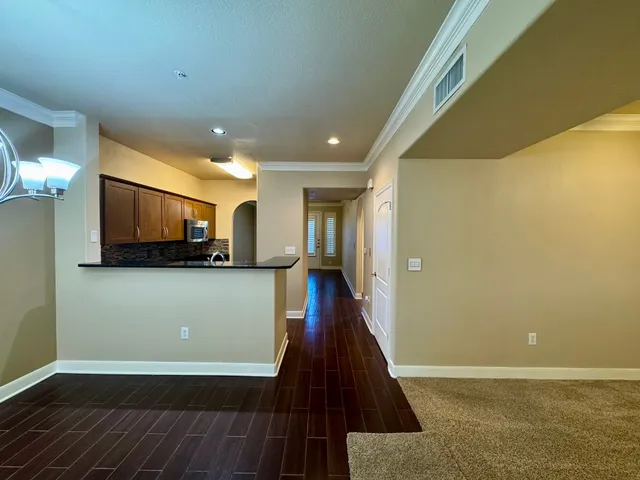 a view of a hallway with wooden floor and a kitchen