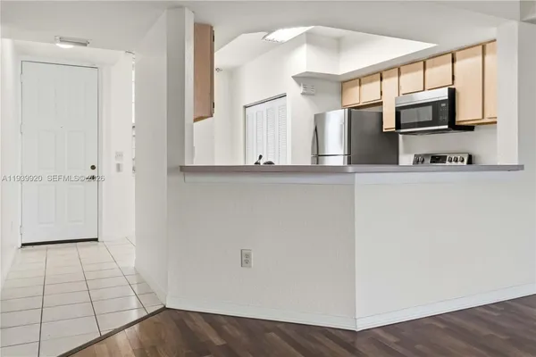 a view of a kitchen with stainless steel appliances wooden floor and a window