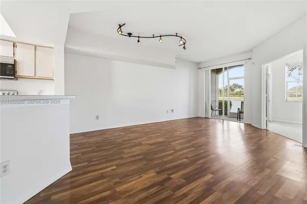 a view of an empty room with window and wooden floor