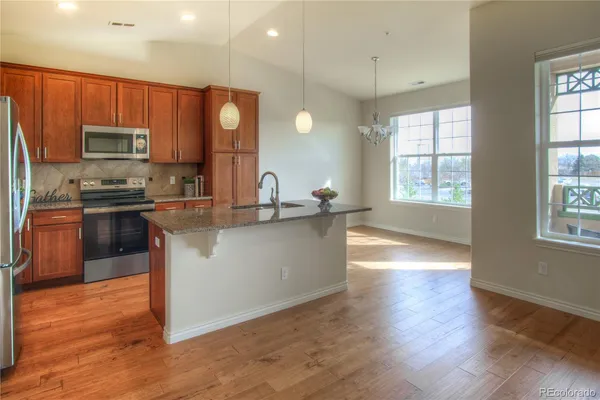 a kitchen with kitchen island granite countertop a sink stove and wooden floor