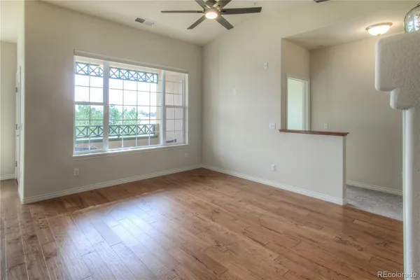 a view of an empty room with wooden floor and a window