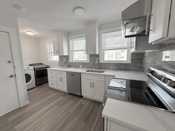 a kitchen with granite countertop a sink stainless steel appliances and window