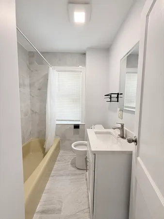 a bathroom with a granite countertop sink a toilet a mirror and bathtub