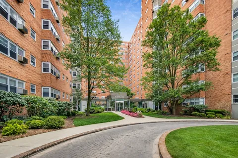 a front view of a building with a yard and trees