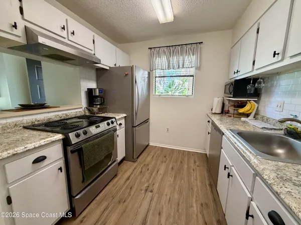 a kitchen with granite countertop a sink a stove and refrigerator