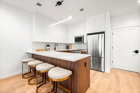a kitchen with stainless steel appliances a table chairs refrigerator and microwave