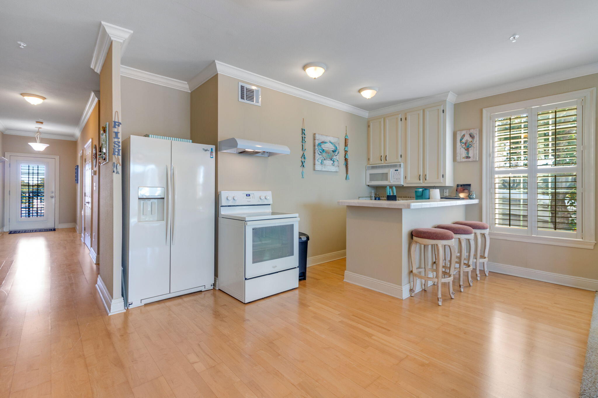 724 Harbor Boulevard, Unit 201 Destin, FL 32541 - Photo 6 of 25 a kitchen with a refrigerator a stove top oven and a dining table with wooden floor