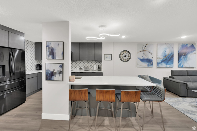 50 Shadow Ridge Road, Unit 4209 Park City, UT 84060 - Photo 10 of 50 Modern kitchen featuring a large island, dark gray cabinetry, stainless steel refrigerator, and patterned tile backsplash
