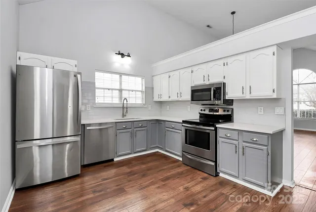 a kitchen with granite countertop white cabinets stainless steel appliances and wooden floor