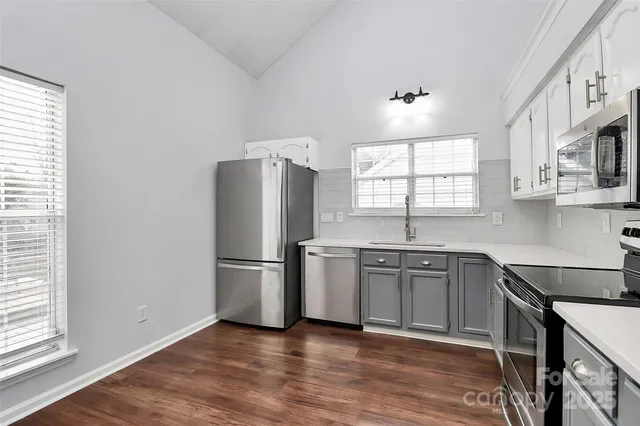 a kitchen with stainless steel appliances granite countertop a refrigerator a sink a stove a microwave and wooden floors