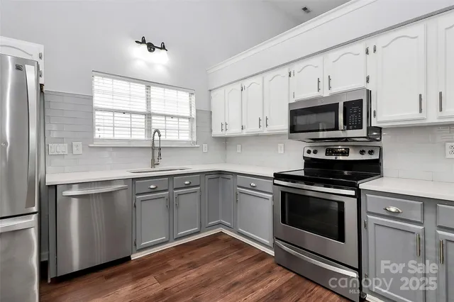 a kitchen with cabinets stainless steel appliances a sink and a window