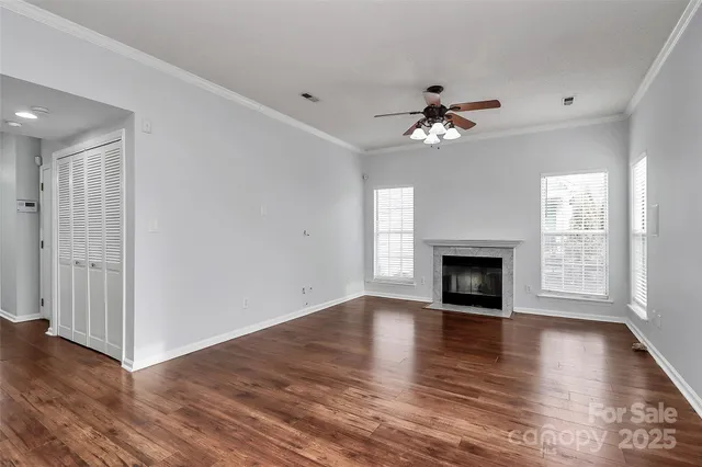 an empty room with wooden floor fireplace and windows