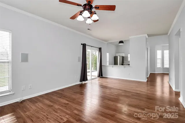 a view of an empty room with window and wooden floor
