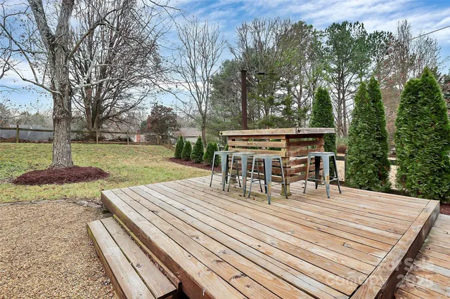 a view of a patio with table and chairs with wooden floor and fence