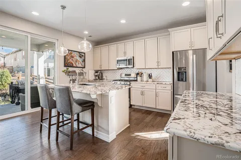 a kitchen with stainless steel appliances granite countertop a table chairs sink refrigerator and cabinets