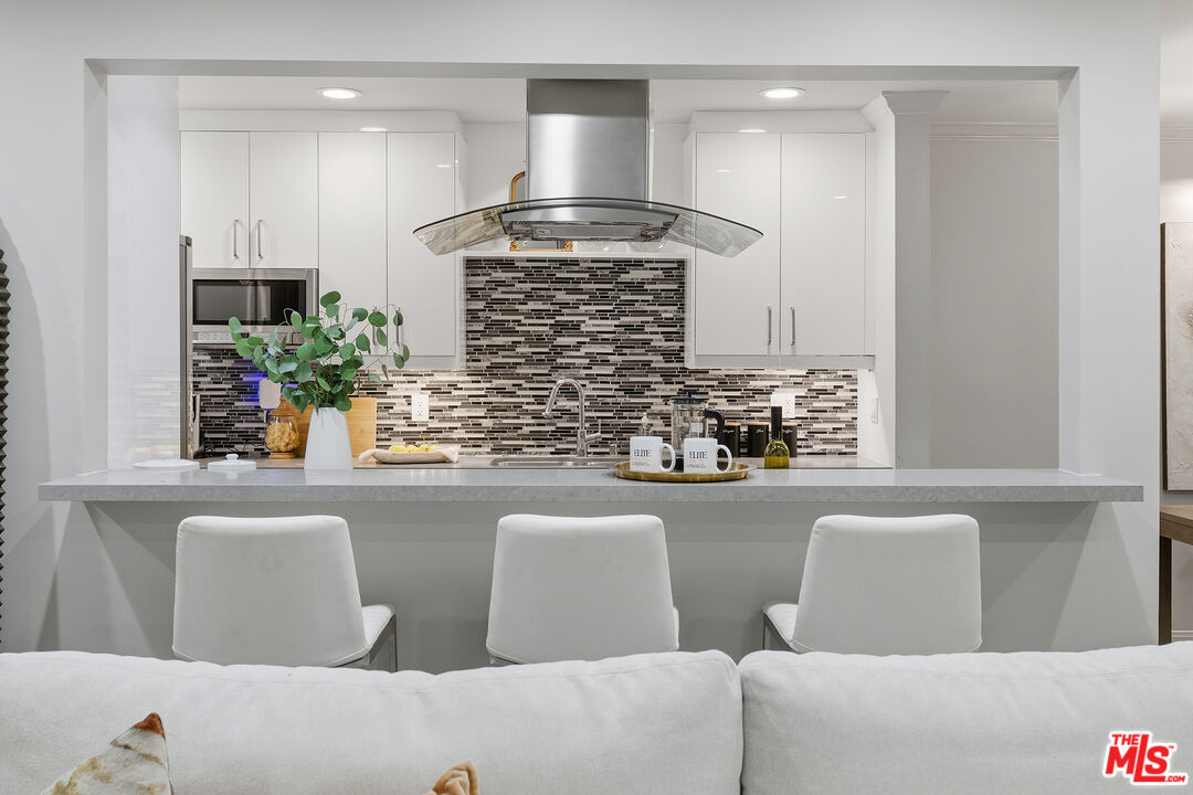 1015 North Kings Road, Unit 110 West Hollywood, CA 90069 - Photo 6 of 36 a kitchen with stainless steel appliances kitchen island granite countertop a refrigerator a stove a microwave oven with a dining table and chairs