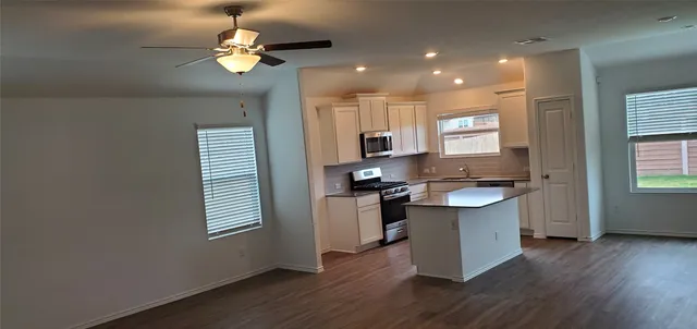 a kitchen with kitchen island stainless steel appliances a sink cabinets and wooden floor
