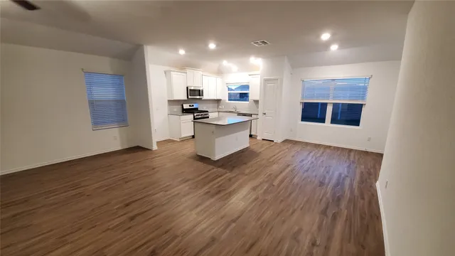 a kitchen with stainless steel appliances wooden floors and large window