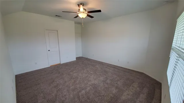 an empty room with a window and a fan