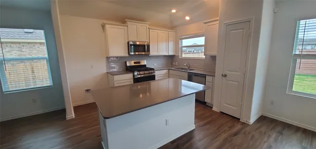 a kitchen with kitchen island granite countertop wooden floors and white stainless steel appliances