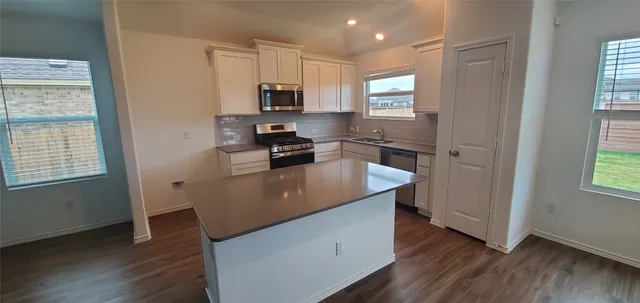 a kitchen with kitchen island granite countertop wooden floors and white stainless steel appliances
