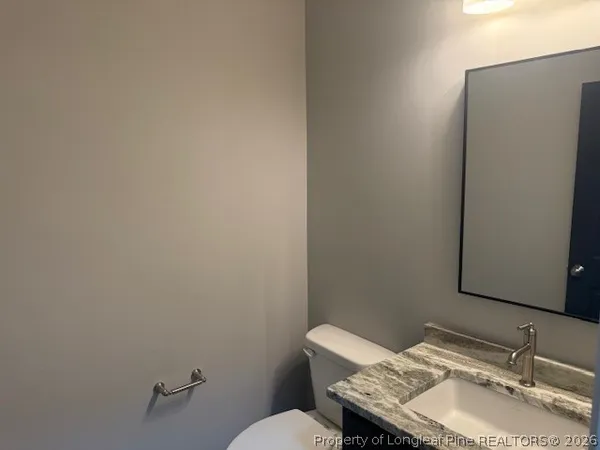 a bathroom with a granite countertop toilet and a sink